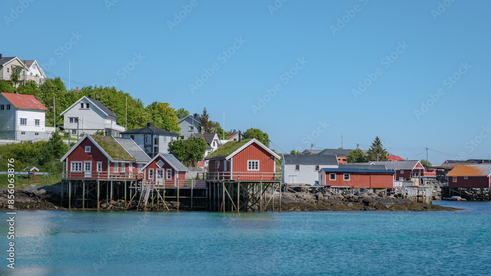 A scenic view of Reine, Lofoten, Norway, waters edge, with a clear blue sky and calm waters in the background. A scenic view of Reine, Lofoten, Norway, waters edge, with a clear blue sky and calm waters in the background.