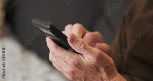 Hands of old man holding checking touching scrolling smartphone, close-up, side view