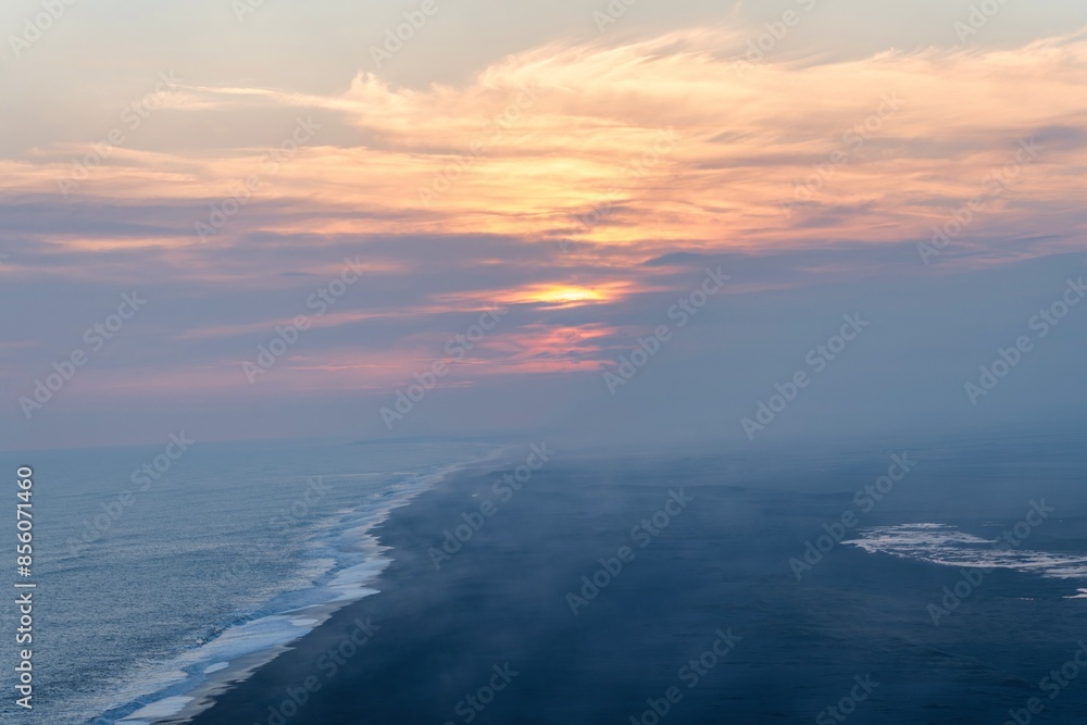 Sunset on the south coast of Iceland with beautiful black sand and orange-red shimmers in the sky Sunset on the south coast of Iceland with beautiful black sand and orange-red shimmers in the sky