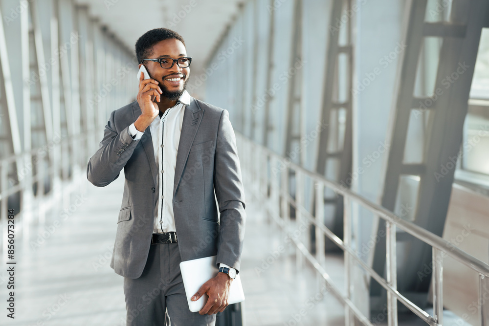 A business traveler black man using his phone with a suitcase at a modern airport. The atmosphere is sleek and professional, reflecting the efficient nature of business trips. A business traveler black man using his phone with a suitcase at a modern airport. The atmosphere is sleek and professional, reflecting the efficient nature of business trips.
