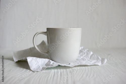 Simple white coffee cup on top of wooden table on light neutral embossed wooden background. Closeup view tea mug mockup. Cosy mug printing design template with copy space. Healthy drink concept.