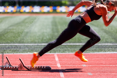 Female sprinter launches from the starting blocks with explosive power