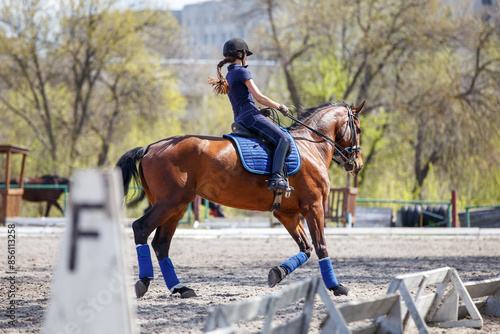Young rider girl riding horse during dressage training