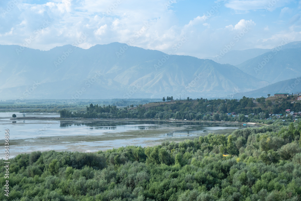 A picturesque scene with a lake, mountains, and a town seen in the distance, lake Wular, Kashmir, India A picturesque scene with a lake, mountains, and a town seen in the distance, lake Wular, Kashmir, India