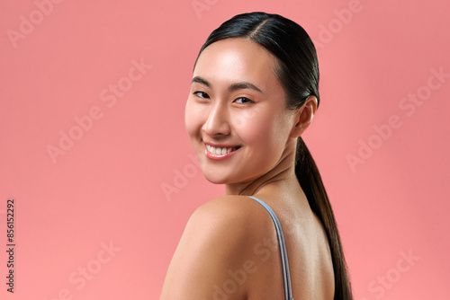 Simplicity and femininity. Portrait of gorgeous woman with no makeup turning head to camera and smiling isolated on pink background. Young lady wearing revealing clothes and looking confident.