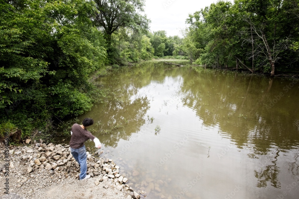 Teen boy throws rock into the river. Teen boy throws rock into the river.