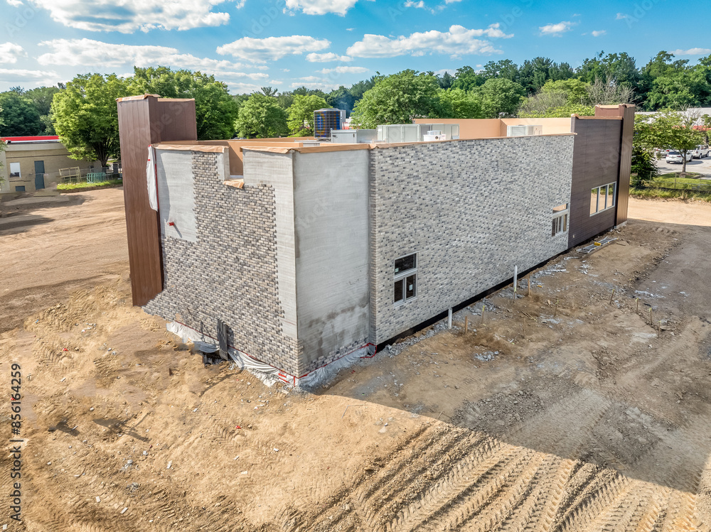 American commercial real estate fast food restaurant building during construction with shade structure entrance, partially installed stone veneer blue sky background