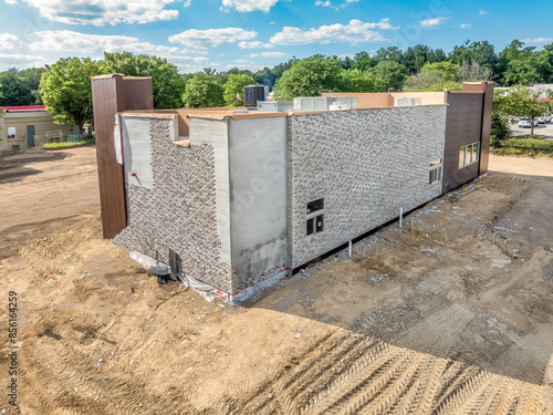 Obraz na płótnie American commercial real estate fast food restaurant building during construction with shade structure entrance, partially installed stone veneer blue sky background w salonie