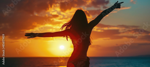 silhouette of a woman with outstretched arms against the background of a beautiful sky and dawn or sunset, a banner of harmony and happiness and summer mood
