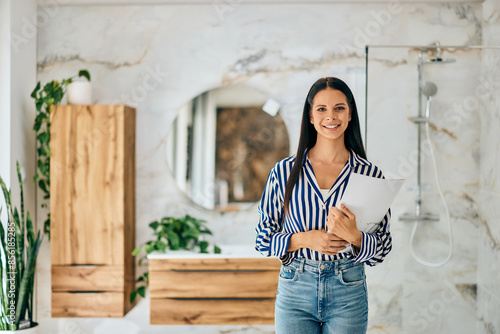 Portrait of a Female Seller, holding some documents, standing in front of the furniture bathroom at the home design shop.