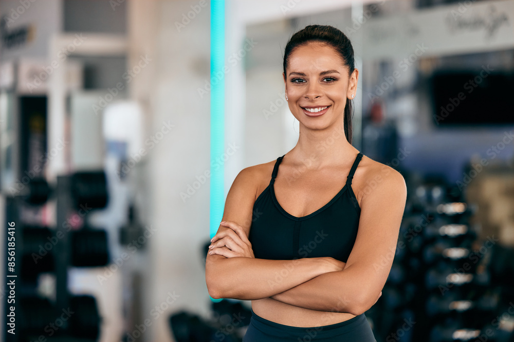 Portrait of a smiling female fitness instructor, holding her hands crossed, posing for the camera, at the gym. Portrait of a smiling female fitness instructor, holding her hands crossed, posing for the camera, at the gym.