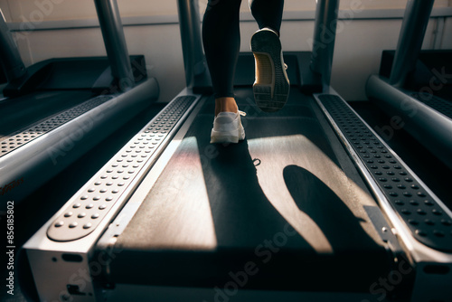 Valokuva A female runner running on a treadmill, close-up of shoes.