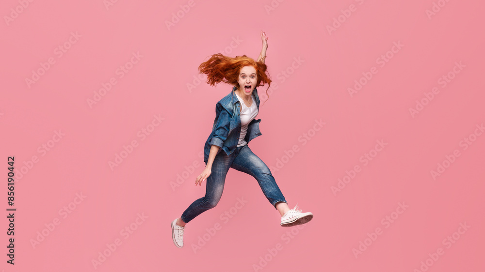 Redhead girl screaming and jumping in air on pink studio background Redhead girl screaming and jumping in air on pink studio background
