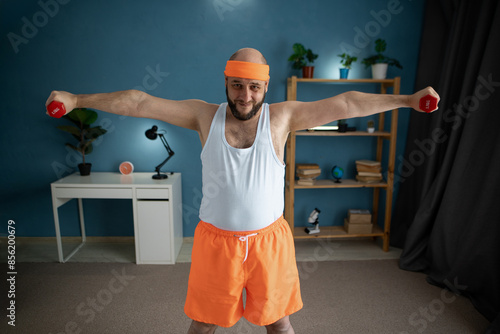 Obraz na plátně Happy active man in orange fitness outfit doing exercise at home