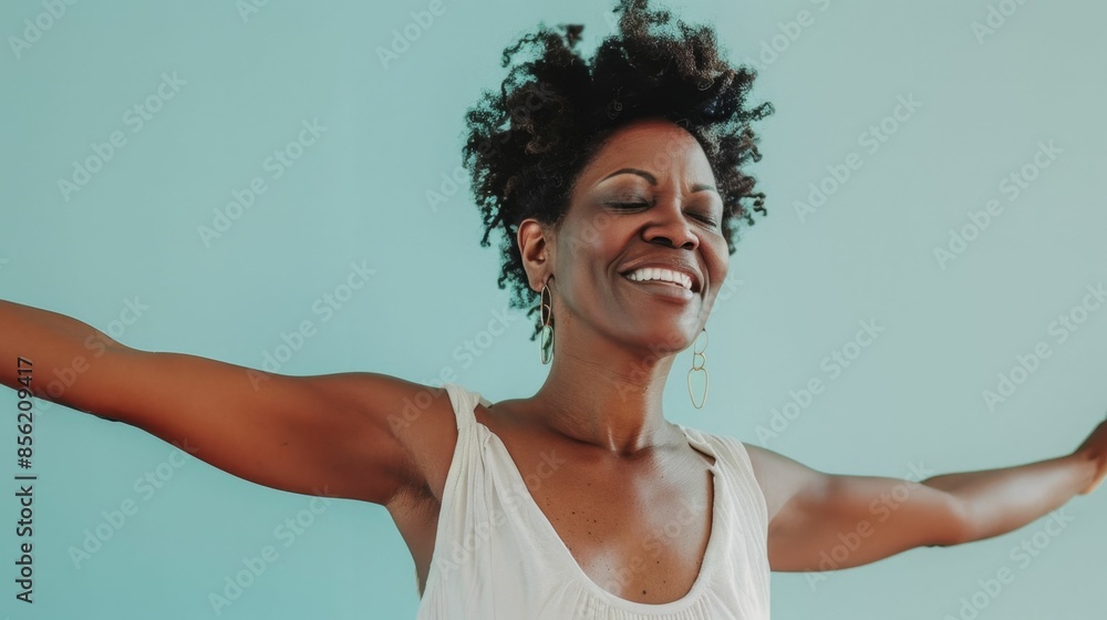 A joyful woman with curly hair smiling broadly and with her arms outstretched in a gesture of happiness or triumph set against a light blue background. A joyful woman with curly hair smiling broadly and with her arms outstretched in a gesture of happiness or triumph set against a light blue background.