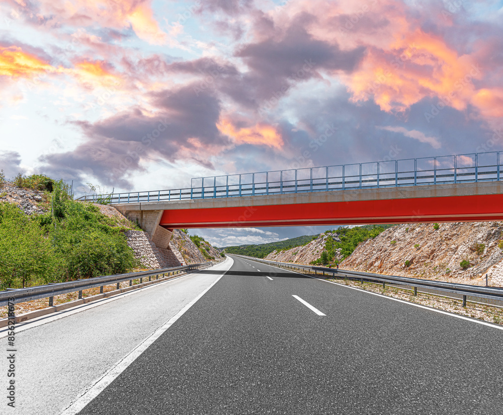 Bridge over the highway. Transport bridge on a highway against the backdrop of mountains.