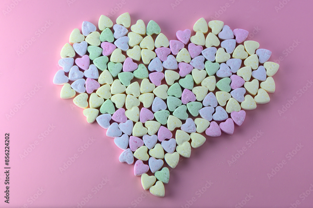 Multicolored heart-shaped candies sprinkled with sugar arrayed on a textured Multicolored heart-shaped candies sprinkled with sugar arrayed on a textured