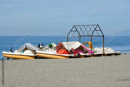 Abandoned pedal boats on the beach and covered with a tarp