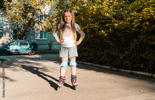 Little girl first ride on a roller skated. Child summer activities concept. Active lifestyle for children.