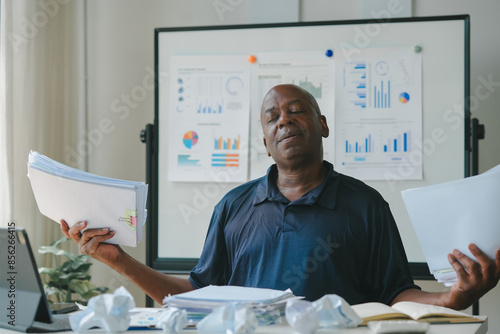 Картината върху платно Stressed businessman surrounded by paperwork, charts, and crumpled documents, indicating a busy and chaotic work environment