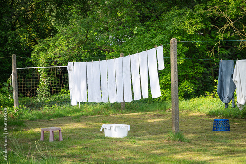 White laundry on clothesline in garden. White towels drying in the sun.
