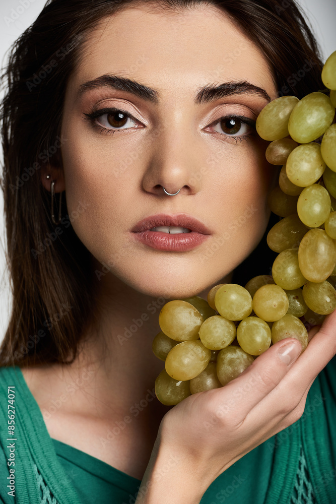 Close-up of young woman with long hair, green dress, grapes. Close-up of young woman with long hair, green dress, grapes.