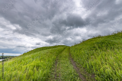 A grassy hill with a dirt road leading up to it