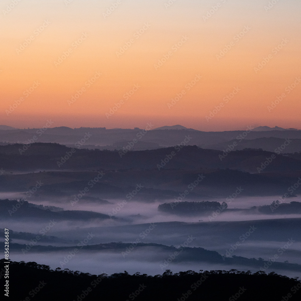 Paisagem de montanhas no amanecer com nuvens baixas e céu laranja Paisagem de montanhas no amanecer com nuvens baixas e céu laranja