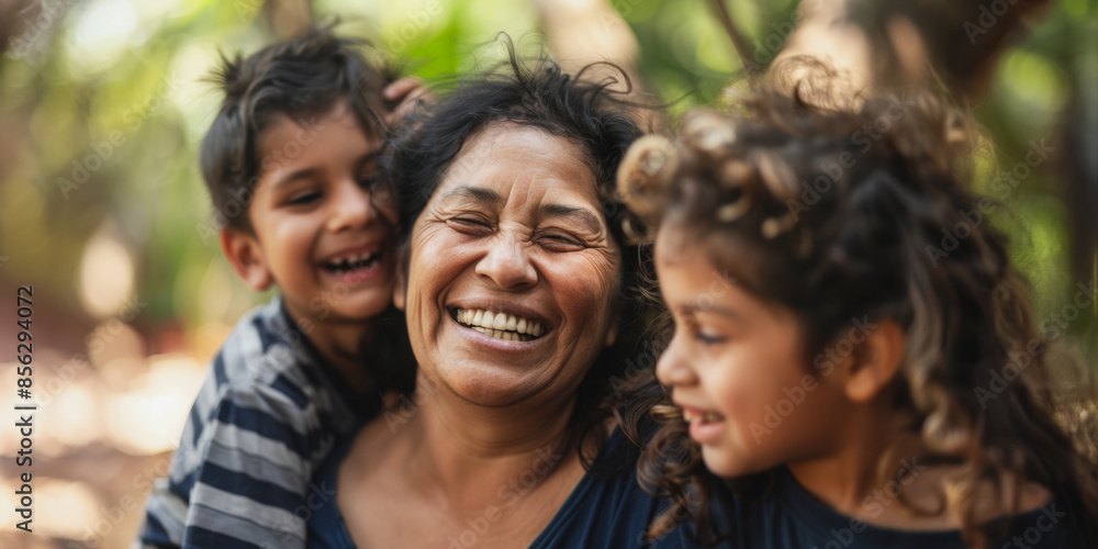 Obraz premium Happy hispanic mother laughing with children in outdoor setting