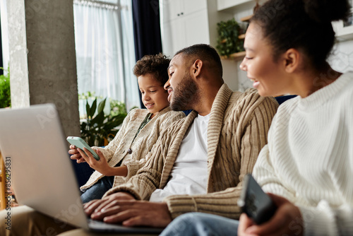 African american family engaged with laptop on couch.