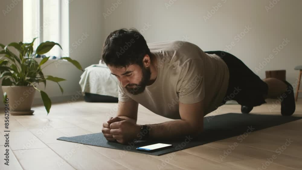 Modern fitness app. Young man doing plank exercise and using mobile application on cellphone Modern fitness app. Young man doing plank exercise and using mobile application on cellphone