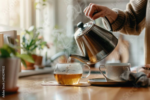 Wallpaper Mural Female hands pouring boiling water from a modern metal stainless kettle in a glass cup for brewing tea in the kitchen at home Torontodigital.ca