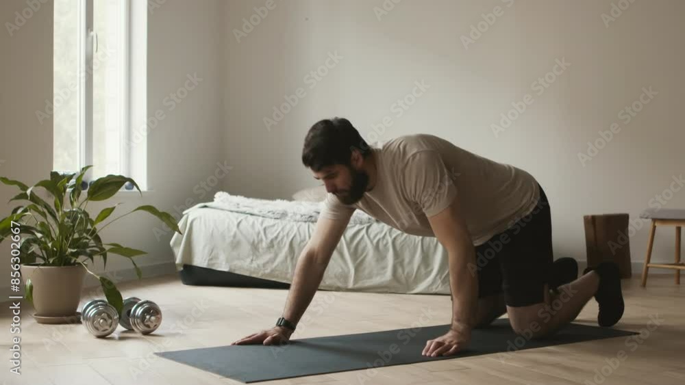 Modern training. Bearded guy using smartwatch before starting doing push ups at home Modern training. Bearded guy using smartwatch before starting doing push ups at home