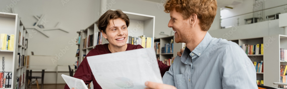 Two male students deeply engrossed in studying a document. Two male students deeply engrossed in studying a document.