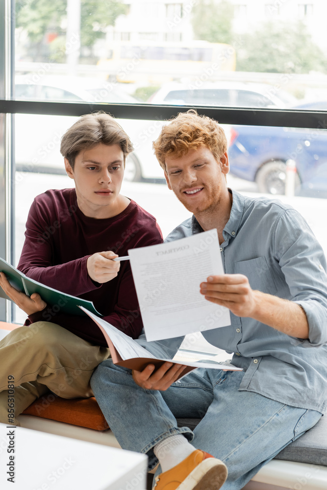Fototapeta premium Two men engage in focused study on a windowsill.