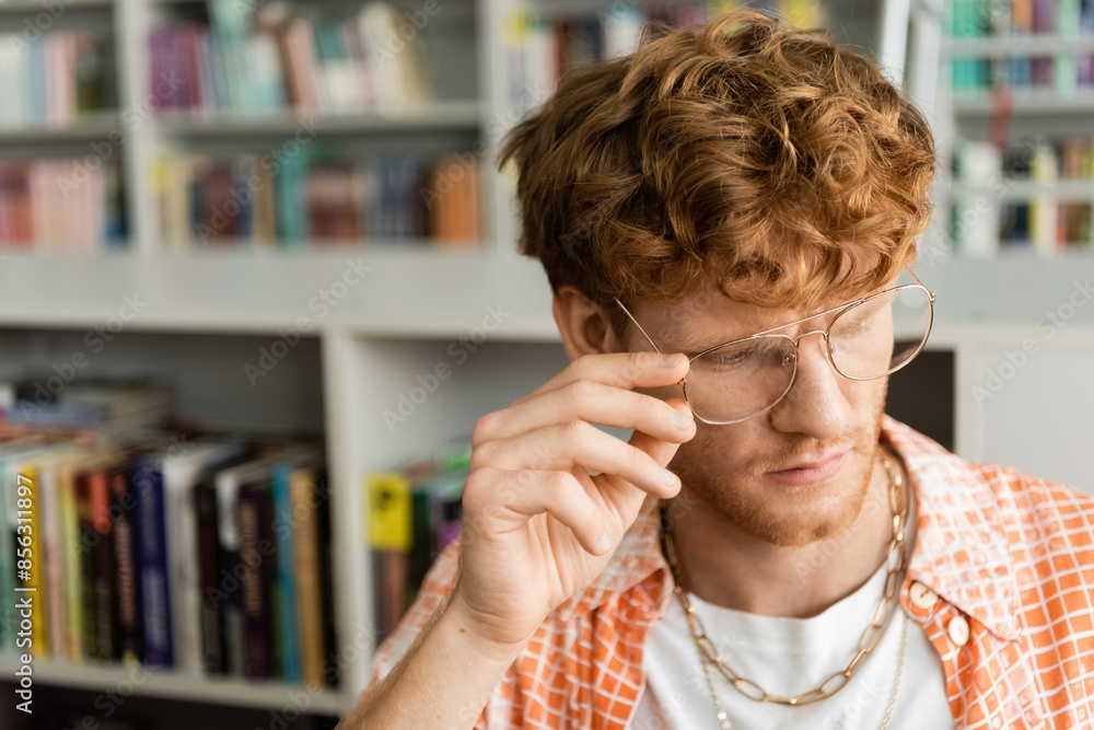A young man with glasses standing in front of a bookshelf. A young man with glasses standing in front of a bookshelf.