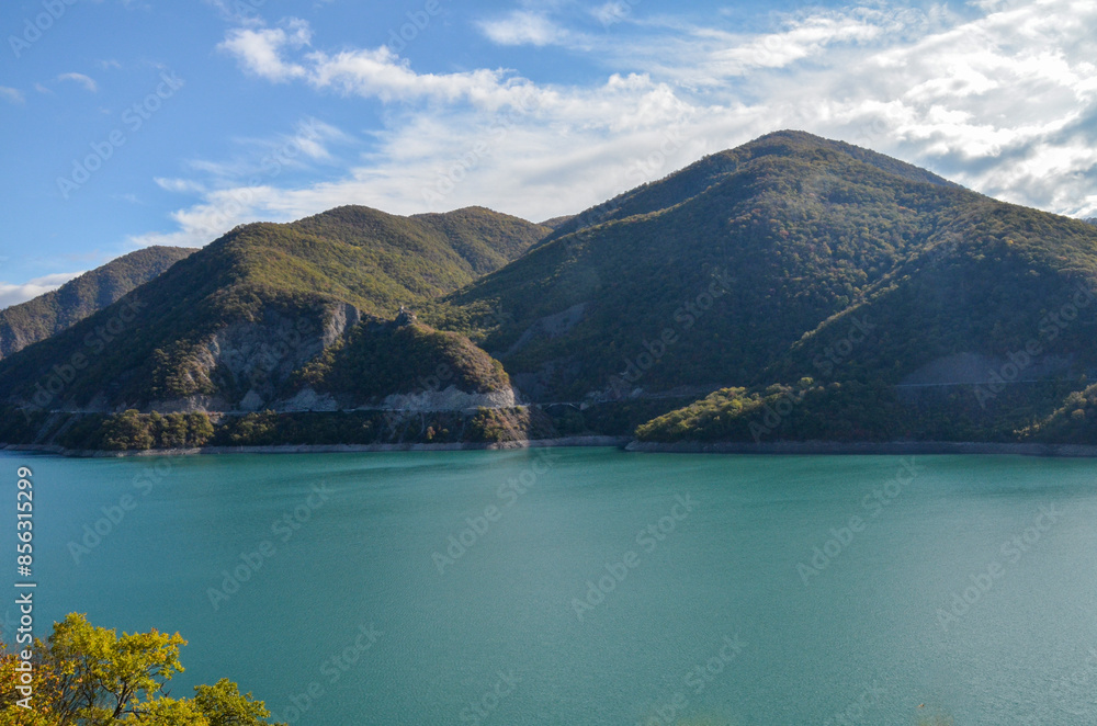 Turquoise water surface reflects the blue sky of Zhinvali Reservoir nestled amidst lush green hills or mountains. Travel to Georgia Turquoise water surface reflects the blue sky of Zhinvali Reservoir nestled amidst lush green hills or mountains. Travel to Georgia
