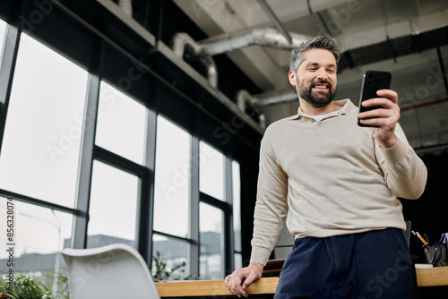 Foto A handsome businessman with a beard smiles as he looks at his phone in a modern office