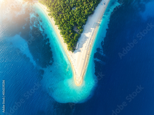 Fototapeta Naklejka Na Ścianę i Meble -  Aerial view of blue sea and Zlatni Rat, Brac island, Croatia in summer. Top drone view of adriatic sea, sandbank, white sandy beach, green trees, azure water at sunset. Tropical landscape. Travel