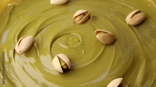 pistachio paste with pistachio nuts in a shell, rotation in circle. Pistachio cream, Turning. selective focus. green background