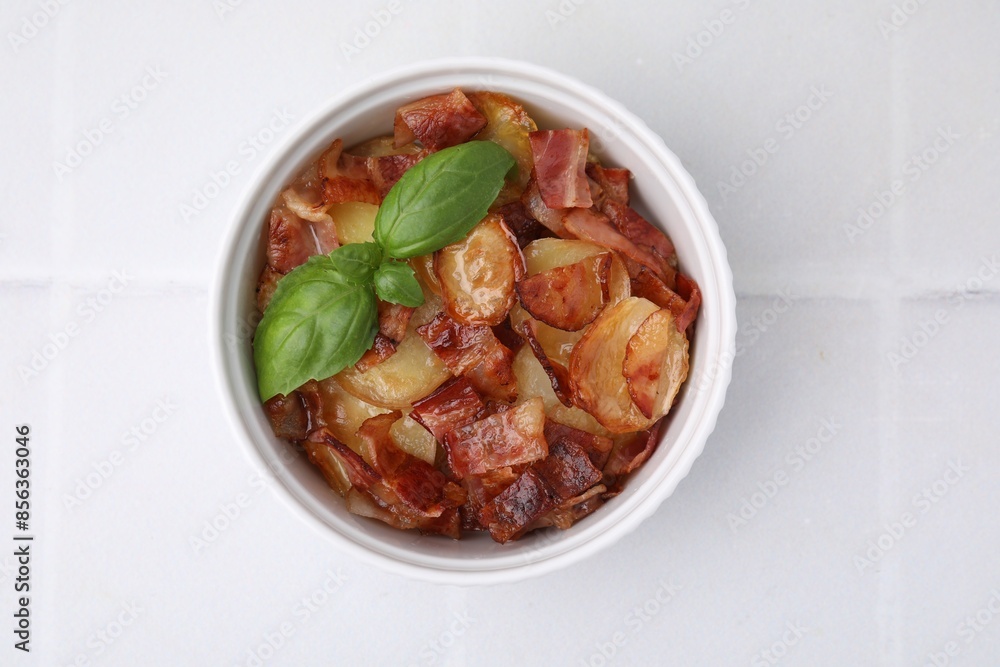 Delicious baked potatoes, bacon and basil in bowl on white table, top view Delicious baked potatoes, bacon and basil in bowl on white table, top view
