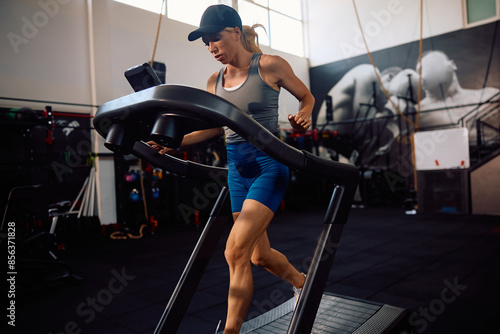 Athletic woman running on treadmill in gym.