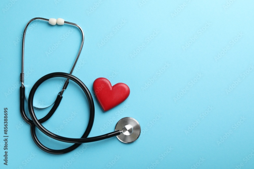 Stethoscope and red heart on light blue background, top view. Space for text Stethoscope and red heart on light blue background, top view. Space for text