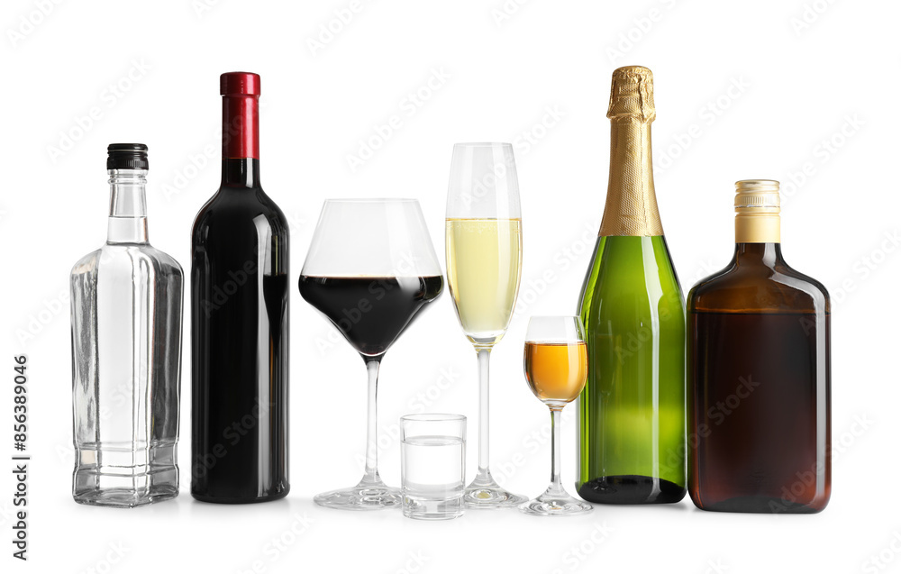 Bottles and glasses with different alcoholic drinks on white table against light background Bottles and glasses with different alcoholic drinks on white table against light background