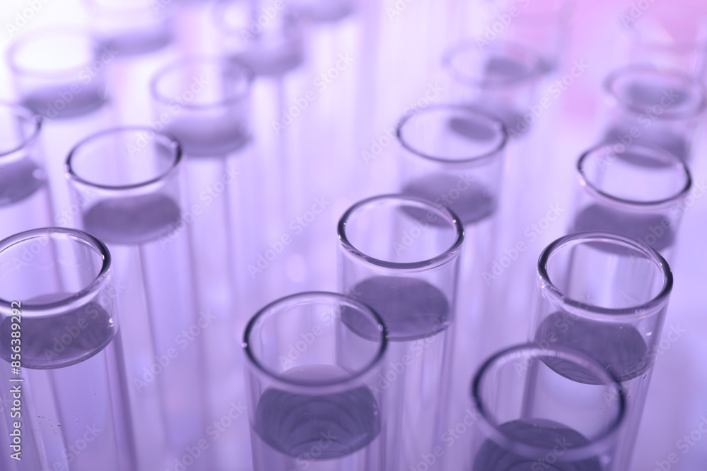 Many glass test tubes on violet background, closeup Many glass test tubes on violet background, closeup