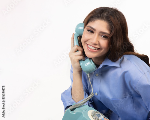 Pretty teenaged girl smiling as she talks on a vintage dial phone.