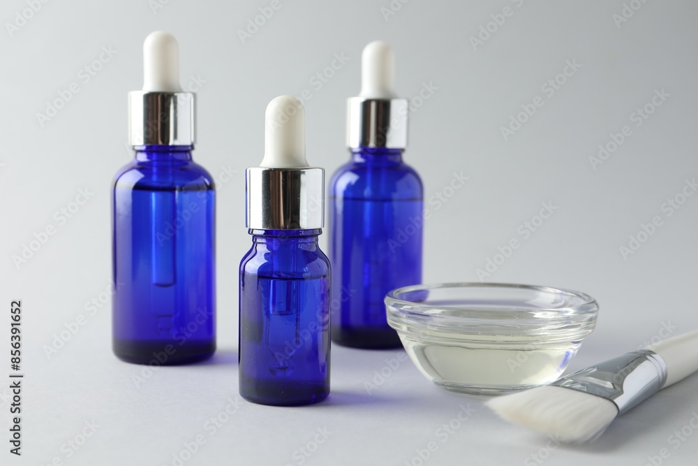 Bottles of chemical peel, bowl with liquid and brush on light background, closeup. Peeling procedure