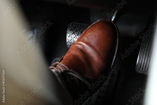 Man pushing on pedal of car brake, closeup