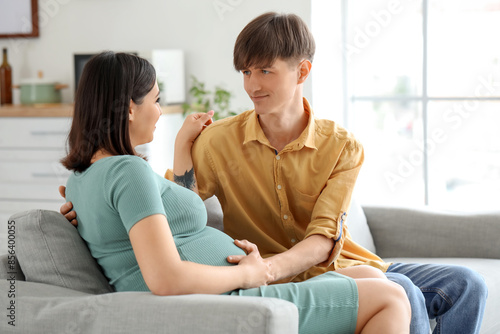 Young pregnant couple sitti...