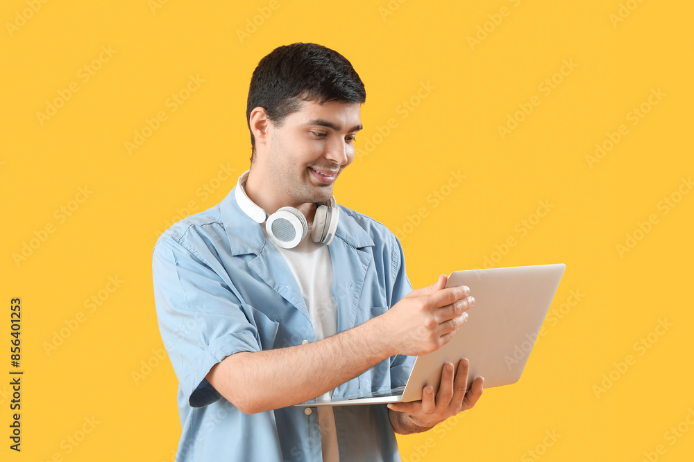 Male programmer working with laptop on orange background Male programmer working with laptop on orange background
